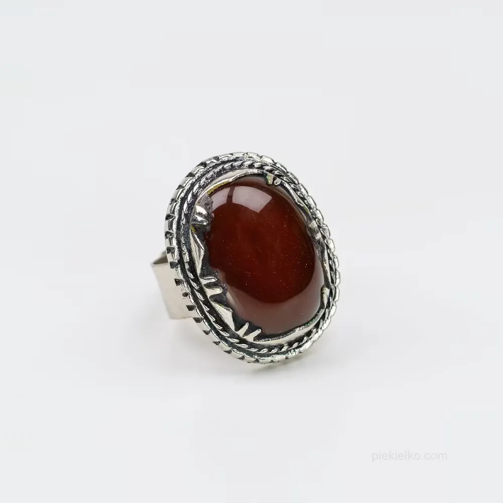 A ring with red glass in a decorative frame